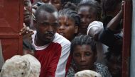 Residents await their turn to obtain food and zinc sheets for roofing at a local distribution center in the city of Jeremie, southwestern Haiti, on October 22, 2016, in the aftermath of Hurricane Matthew. AFP / Hector Retamal