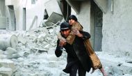 A Syrian rescuer carries a woman who was rescued from the rubble of a building following reported airstrikes on Aleppo's rebel-held district of Al Hamra, yesterday.