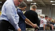 Potential buyers try out guns which are displayed on an exhibitor's table during the Nation's Gun Show on November 18, 2016 at Dulles Expo Center in Chantilly, Virginia. Alex Wong/Getty Images/AFP