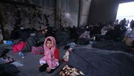 TOPSHOT - A Syrian boy, who fled with his family from rebel-held areas in the city of Aleppo, sits on November 30, 2016, inside a shelter in the neighberhood of Jibrin, east of Aleppo. / AFP.