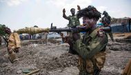 soldiers of the Sudan People Liberation Army (SPLA) celebrate while standing in trenches in Lelo, outside Malakal, northern South Sudan, on October 16, 2016. Heavy fighting broke out on Ocotober 14 between SPLA (Government) and opposition forces in Wajwok