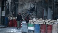 A rebel fighter stands with his weapon near damaged buildings, and barricades with a Free Syrian Army flag drawn(C), in rebel-held besieged old Aleppo, Syria December 2, 2016. REUTERS/Abdalrhman Ismail
