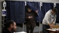 A man leaves a voting booth with his ballot during a referendum on constitutional reforms, on December 4, 2016 at a polling station in Milan.  AFP / MARCO BERTORELLO
