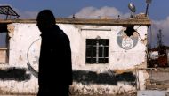 A man walks near a damaged Islamic State sign in government controlled Hanono housing district in Aleppo, Syria December 4, 2016. REUTERS/Omar Sanadiki