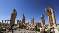 Journalists walk near the remains of the Monumental Arch in the historical city of Palmyra, in Homs Governorate, Syria April 1, 2016. REUTERS/Omar Sanadiki/File Photo