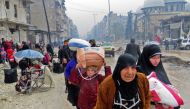 Syrian residents, fleeing violence in the restive Bustan al-Qasr neighbourhood, arrive in Aleppo's Fardos neighbourhood on December 13, 2016, after regime troops retook the area from rebel fighters.  AFP / STRINGER
