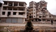 A member of forces loyal to Syria's President Bashar al-Assad sits near damaged buildings in Aleppo's Salaheddine district, Syria December 16, 2016. REUTERS/Omar Sanadiki