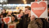 A protester holds a sign with a red heart reading the hashtags 'spreadlove' and 'stophate' during an anti right wing demonstration near the place of the terror attack on a Christmas market in Berlin on December 21, 2016. AFP / CLEMENS BILAN