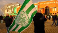 A Celtic fan with a flag stands outside Celtic Park in Glasgow on December 17, 2016 before the Scottish Premiership football match between Celtic and Dundee United.  AFP / ANDY BUCHANAN 

