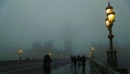 Pedestrians cross Westminster Bridge on a foggy morning in central London, yesterday.