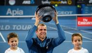 Gilles Muller of Luxembourg holds up his trophy with his sons Lenny and Nils after beating Daniel Evans of Britain in the men's singles final match at the Sydney International tennis tournament in Sydney on January 14, 2017.  AFP / Peter PARKS