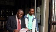 Zimbabwean Pastor Phillip Patrick Mugadza (R) is escorted by detectives at the Harare Magistrates court, where he faces charges of insulting President Robert Mugabe for allegedly prophesing the statesman would die on October 17 this year, according to the