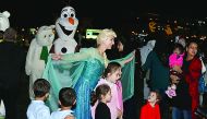 Children take photos with street performers at the fourth Katara Winter Festival.