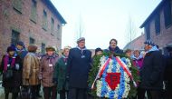 Survivors stand before laying a wreath in front of the 
