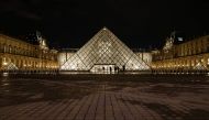 People stand outside the Louvre Pyramid of the Louvre museum at night on February 3, 2017, in Paris, after a French soldier patrolling at the Louvre shot and seriously injured a machete-wielding attacker earlier.