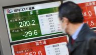 A businessman looks at an electric quotation board flashing the share price of Japan's Toshiba (top/L) in front of a securities company in Tokyo on February 15, 2017.  AFP / TORU YAMANAKA
