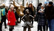 FILE PHOTO: People look at a statue of a girl facing the Wall St. Bull, as part of a campaign by U.S. fund manager State Street to push companies to put women on their boards, in the financial district in New York, U.S., March 7, 2017. REUTERS/Brendan McD