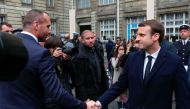 French centrist presidential candidate Emmanuel Macron (R) shakes hands with Etienne Cardiles, the partner of the policeman killed by a jihadist in an attack on the Champs Elysees, on April 25, 2017, during a ceremony at the Paris prefecture building. AFP