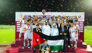 The players and officials of Jordan team celebrate on the podium during the medals ceremony of the fifth Asian Communities Football Tournament in Doha on Friday.