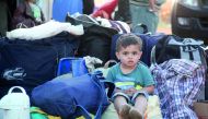 A Syrian child who was a part of a convoy of opposition fighters and their families, evacuated from the Waer neighbourhood, the last opposition-held district in the central city of Homs, sits after their arrival in the Maaret Al Ikhwaan village north of I