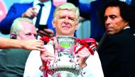 Arsenal manager Arsene Wenger smiles as he holds the FA Cup trophy after their win over Chelsea in the final match at Wembley Stadium in London in this May 27 file picture.