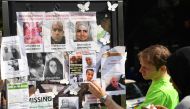 People look at images of missing people, placed on a phone box near to the Grenfell Tower, a residential tower block in Kensington, west London, on June 19, following the June 14 fire which gutted the residential building. (AFP / Paul ELLIS)