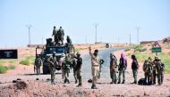 Syrian government forces gesture and inspect the site as they arrive at a destroyed bridge on a road between the Kabajeb and Al Shula on the southwestern outskirts of Deir Ezzor, yesterday.
