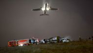 A plane passes as firefighters attempt to extinguish a burning private airplane after crashing at Ataturk Airport on September 21, 2017 in Istanbul.  AFP / Ozan Kose