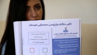 An employee from the Independent High Electoral Referendum Commission holds a voting ballot book at a voting station ahead of tomorrow's planned referendum for the Kurdistan region, in Arbil, the capital of the autonomous Kurdish region of northern Iraq, 