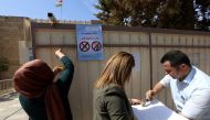 Employees from the Independent High Electoral Referendum Commission hang banners outside a voting station ahead of tomorrow's planned referendum for the Kurdistan region, in Arbil, the capital of the autonomous Kurdish region of northern Iraq, on Septembe