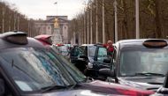 (FILES) This file photo taken on February 10, 2016 shows a driver standing by his vehicle as taxi drivers block The Mall as they demonstrate in central London on February 10, 2016 against UBER. AFP / JUSTIN TALLIS
