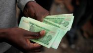 This file photo taken on November 28, 2016 shows a man holding bond notes released by the Reserve Bank Of Zimbabwe in Harare central business centre.  AFP / Wilfred Kajese