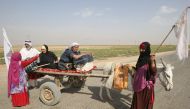 Members of an Iraqi family, displaced from the outskirts of Islamic State (IS) group stronghold Hawija (about 65 kilometres east of the northern city of Kirkuk), raise white flags while travelling with a donkey-cart on the road outside the town on October