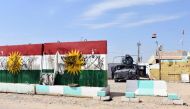 Iraqi army forces stand guard at a former Kurdish military position, bearing a defaced Kurdish flag, on October 13, 2017 in the northern Iraqi town of Taza Khurmatu, near Iraq's oil-rich multi-ethnic province of Kirkuk.  AFP / Marwan IBRAHIM
