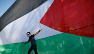 A Palestinian youth poses in front of his national flag during celebrations in Gaza City after rival Palestinian factions Hamas and Fatah reached agreement on October 12, 2017 (AFP / Mohammed Abed) 
