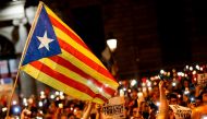 People hold candles and a Catalan pro-independence 'Estelada' flag during a demonstration in Barcelona against the arrest of two Catalan separatist leaders on October 17, 2017. AFP / PAU BARRENA