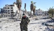 A member of the Syrian Democratic Forces (SDF) walks through a heavily damaged a street leading to an Armenian church in Raqa on October 18, 2017. AFP / Bulent Kilic
