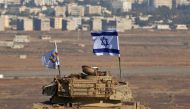 An Israeli flag flutters above the wreckage of an Israeli tank sitting on a hill in the Israeli-occupied sector of the Golan Heights and overlooking the border with Syria and the town of Quneitra, on October 18, 2017.  AFP / Jalaa Marey