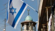 An Israeli flag waves in front of the minaret of a mosque in the Arab quarter of Jerusalem Old City on November 14, 2016 (AFP)
