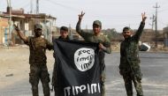 Iraqi members of the Hashed al-Shaabi (Popular Mobilisation units) carry an upsidedown Islamic State (IS) group flag in the city of al-Qaim, in Iraq's western Anbar province near the Syrian border as they fight against remnant pockets of Islamic State gro