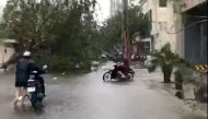 Motorcyclists pass fallen trees along a street during a storm in Nha Trang, as Typhoon Damrey descends on southern Vietnam, in this still image taken from social media video, November 4, 2017. @AMALZIAQ/via REUTERS