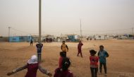 Syrian refugee children play during a sand storm at the Zaatari refugee camp on November 13, 2017. Some 80,000 Syrian refugees living in the Zaatari camp will have access to 14 hours of electricity per day instead of eight hours, thanks to the opening of 
