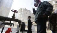 Syrians standing next to water faucets as they fill jerrycans in al-Shaar neighbourhood, Aleppo on January 21, 2017 (AFP / Louai Beshara) 