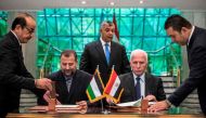 (FILES) This file photo taken on October 12, 2017 shows Fatah's Azzam al-Ahmad (R) and Saleh al-Aruri (L) of Hamas signing a reconciliation deal at the Egyptian intelligence services headquarters in Cairo, as the two rival Palestinian movements ended thei