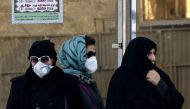  Iranian women wearing face masks wait at a bus stop as winter's heavy pollution has hit new highs in the capital Tehran, on December 17, 2017. / AFP / ATTA KENARE