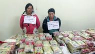 This picture taken on January 2, 2018 shows arrested ethnic H'mong couple Vu Chu Senh (R), 44, and his wife Mua Thi Do, 39, posing behind a table with 489 packs of heroin (170 kgs) they attempted to smuggle into Vietnam from Laos, at a police station in t