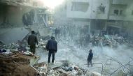 People stand on rubble of damaged buildings, after an airstrike in the besieged town of Hamoria, Eastern Ghouta, in Damascus, Syria Janauary 9, 2018. Reuters/Bassam Khabieh