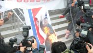 South Korean protestors burn a picture of North Korean leader Kim Jong-Un during an anti-North Korea rally outside Seoul station in Seoul on January 22, 2018 as a North Korean delegation arrives at the station. South Korea OUT / AFP / Dong-A Ilbo / -
