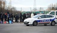 A police vehicle passes by people gathering in Calais, northern France, on February 2, 2018, a day after a large brawl between a hundred migrants resulted in several injuries.  AFP / Philippe Huguen