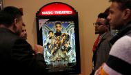A group of men gather in front of a poster advertising the film 